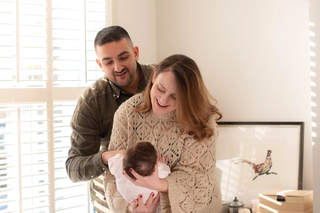 Man and woman smiling and looking down at their newborn baby