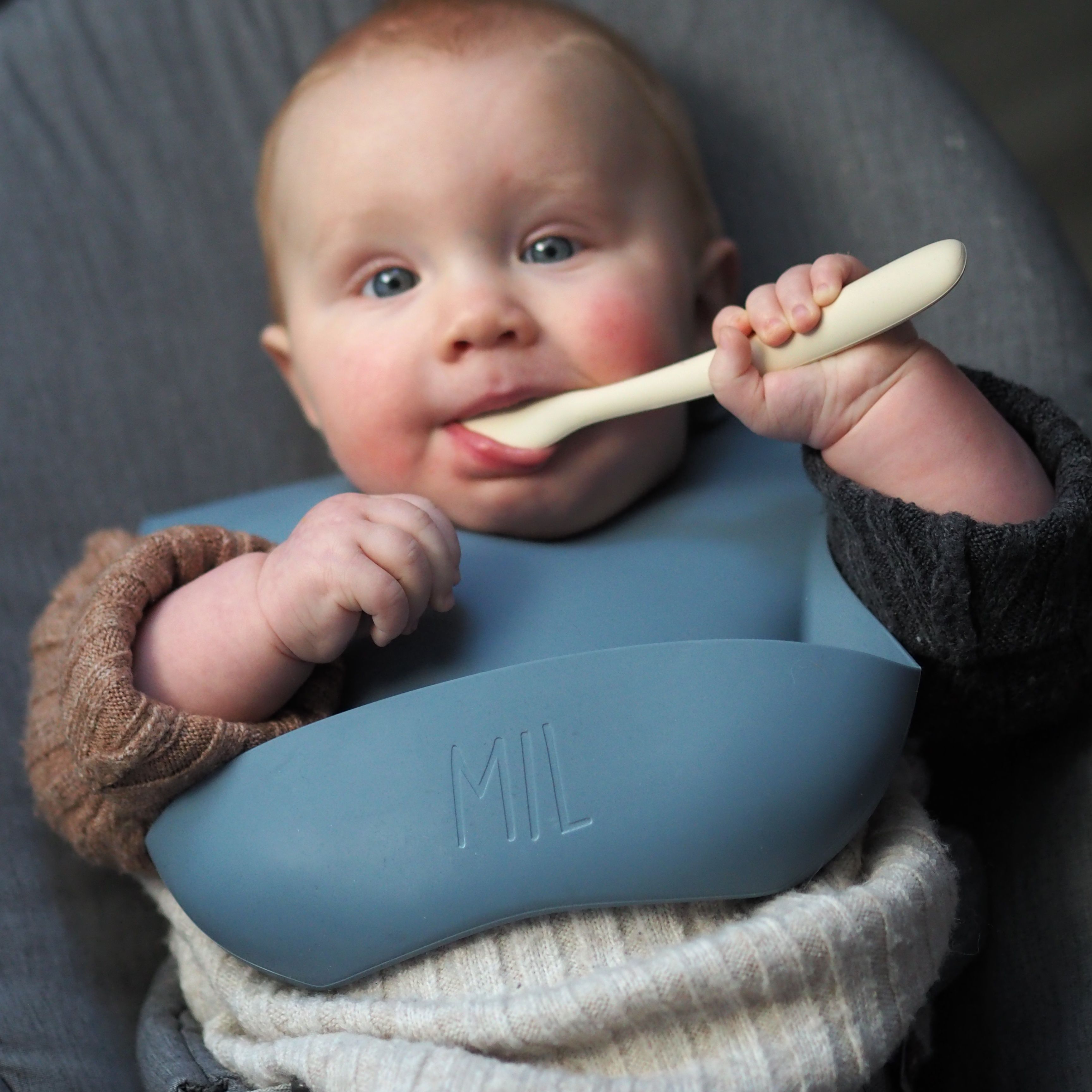 Baby mit Lätzchen mit Löffel im Mund