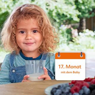 Ein kleines Kind mit lockigem Haar, das ein Glas Milch in der Hand hält, vor einem Gartenhintergrund mit einem Kalender, auf dem "17. Monat mit dem Baby".