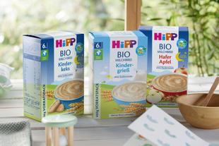 Drei Schachteln mit Babynahrung mit den Aufschriften "BIO MILCHBREI", "BIO MILCHBREI Kinder-Gries" und "BIO MILCHBREI Hafer Apfel", jede mit einer anderen Geschmacksrichtung und Nährwertangaben.