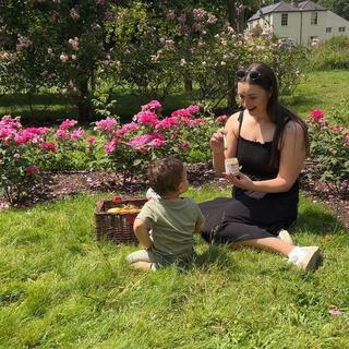 Lauryn McCabe at a picnic with her little one, feeding them a HiPP Organic baby food jar
