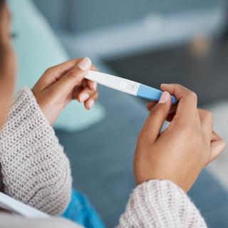 Eine Person hält einen Ovulationstest in der Hand.