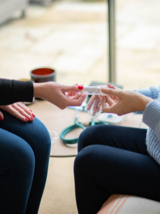 Healthcare professional handing a pregnant woman a urine sample pot