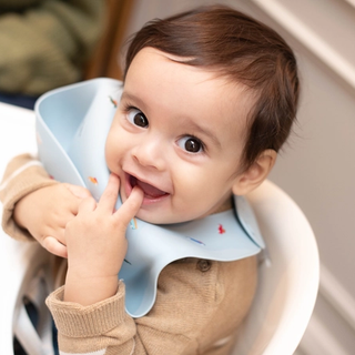Baby boy sat in highchair playing with bib