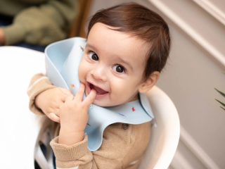 Baby boy sat in highchair playing with bib