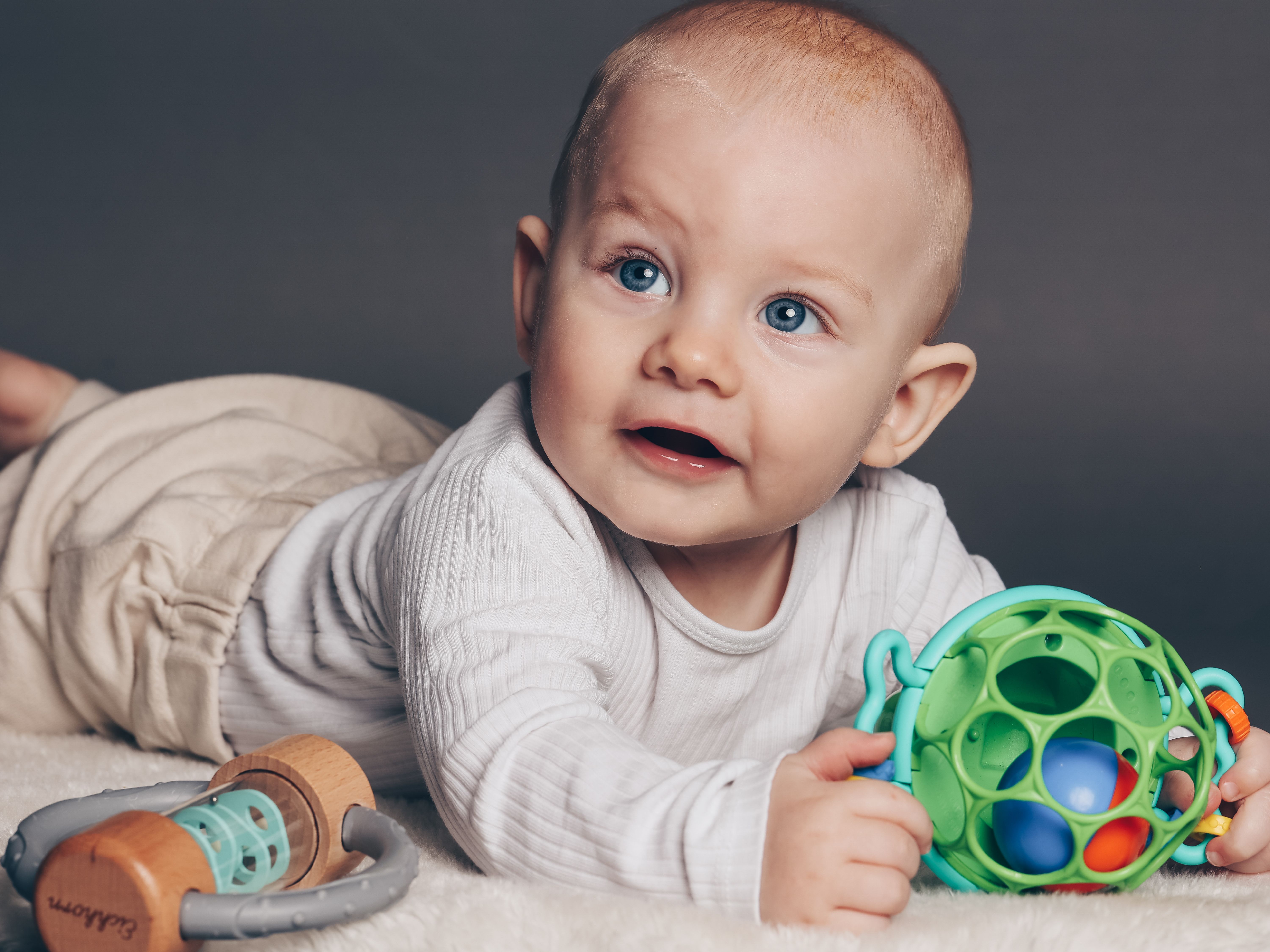 Baby liegt auf Bauch mit Spielzeug