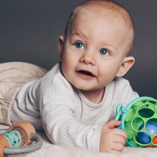Baby liegt auf Bauch mit Spielzeug