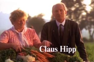 Älteres Paar steht bei Sonnenuntergang hinter einem Tisch mit frischem Bio-Gemüse wie Karotten, Blumenkohl und Kräutern.