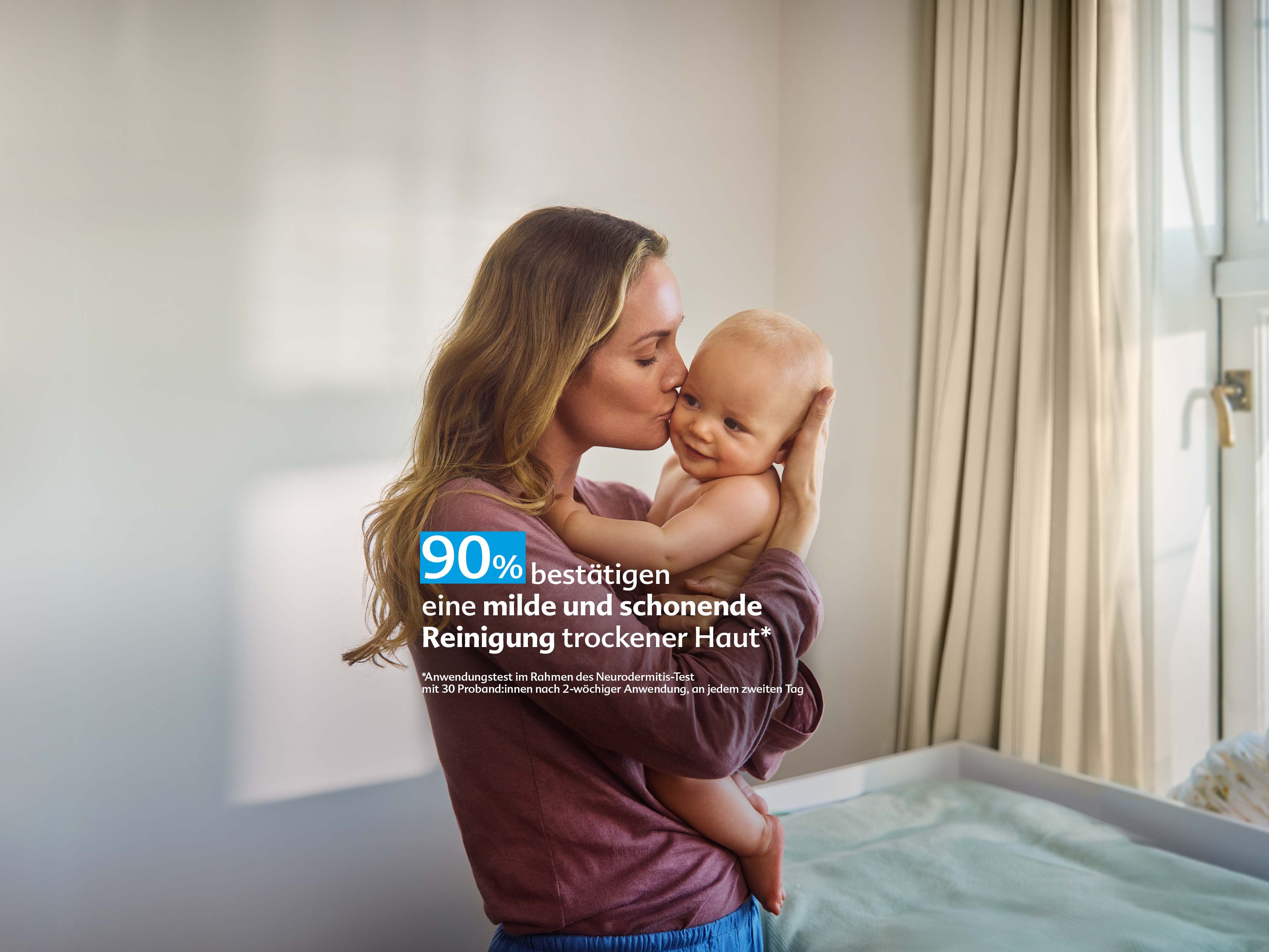 Mutter hält ihr Baby liebevoll im Arm und küsst es, daneben Text: „90 % bestätigen eine milde, schonende Reinigung trockener Haut“.