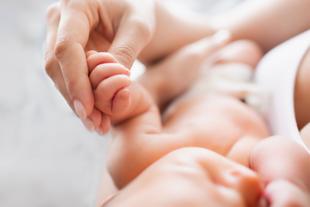 Eine Mutter hält sanft die Hand ihres Babys, während es gestillt wird.