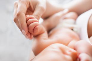 Eine Mutter hält sanft die Hand ihres Babys, während es gestillt wird.
