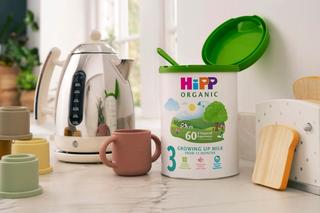 HiPP Organic Growing Up Milk powder tin showing the scoop, next to a kettle and cup