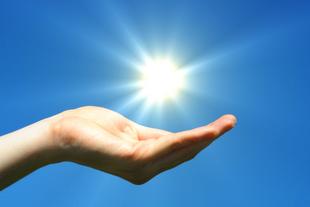 Geöffnete Hand unter strahlender Sonne vor blauem Himmel als Symbol für Vitamin D, das Sonnenvitamin für starke Knochen