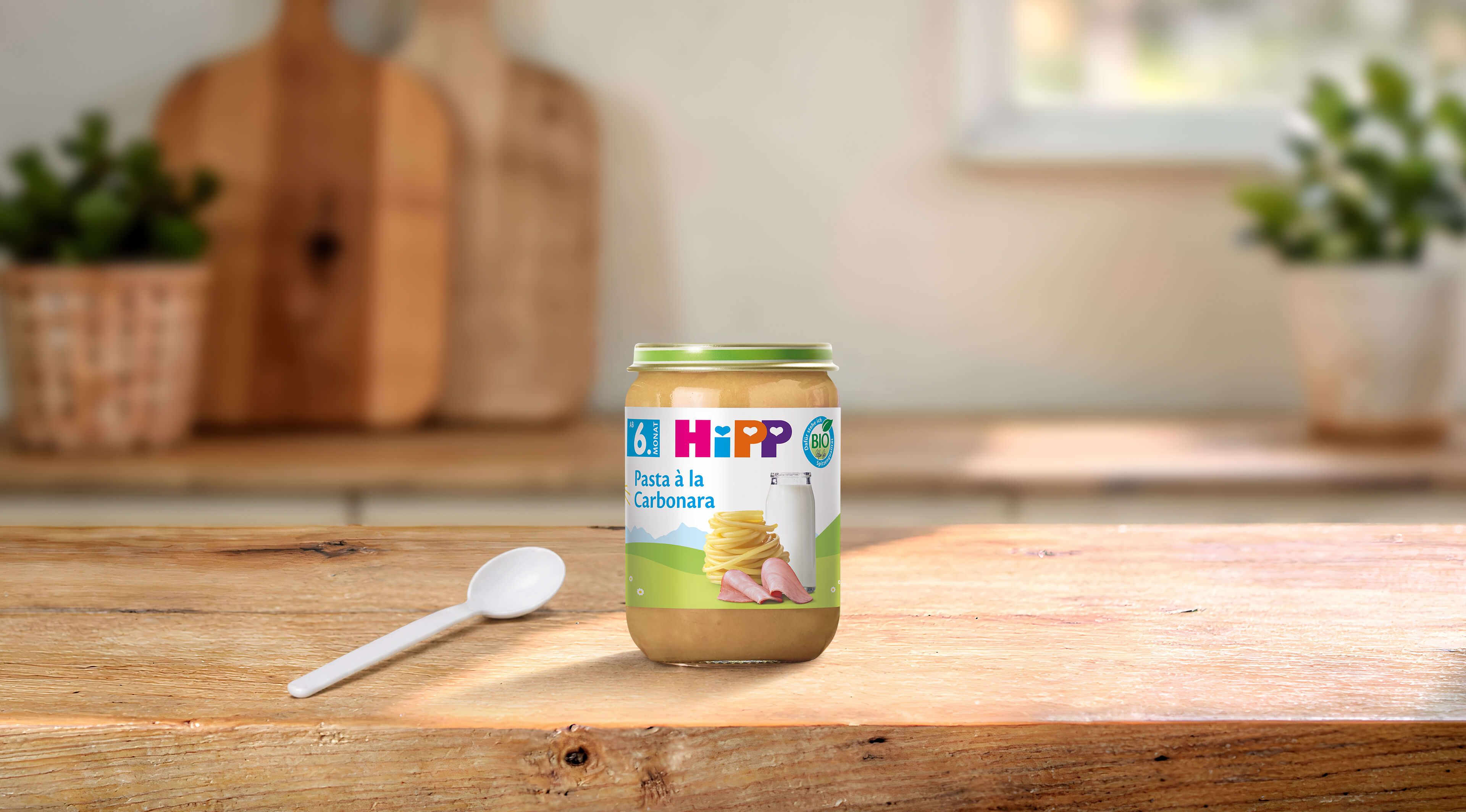 HiPP Bio Pasta à la Carbonara im 190-g-Glas mit Löffel auf einem Holztisch