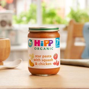 HiPP Organic Star pasta with Squash & Chicken on a dining table next to a bowl and spoon