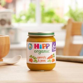HiPP Organic Carrots & Peas on a dining table next to a bowl and spoon