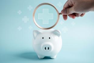 Weiße Sparschwein-Spardose, darüber eine Lupe mit Gesundheitskreuz – symbolisiert Kosten und Finanzierung der Stillberatung.