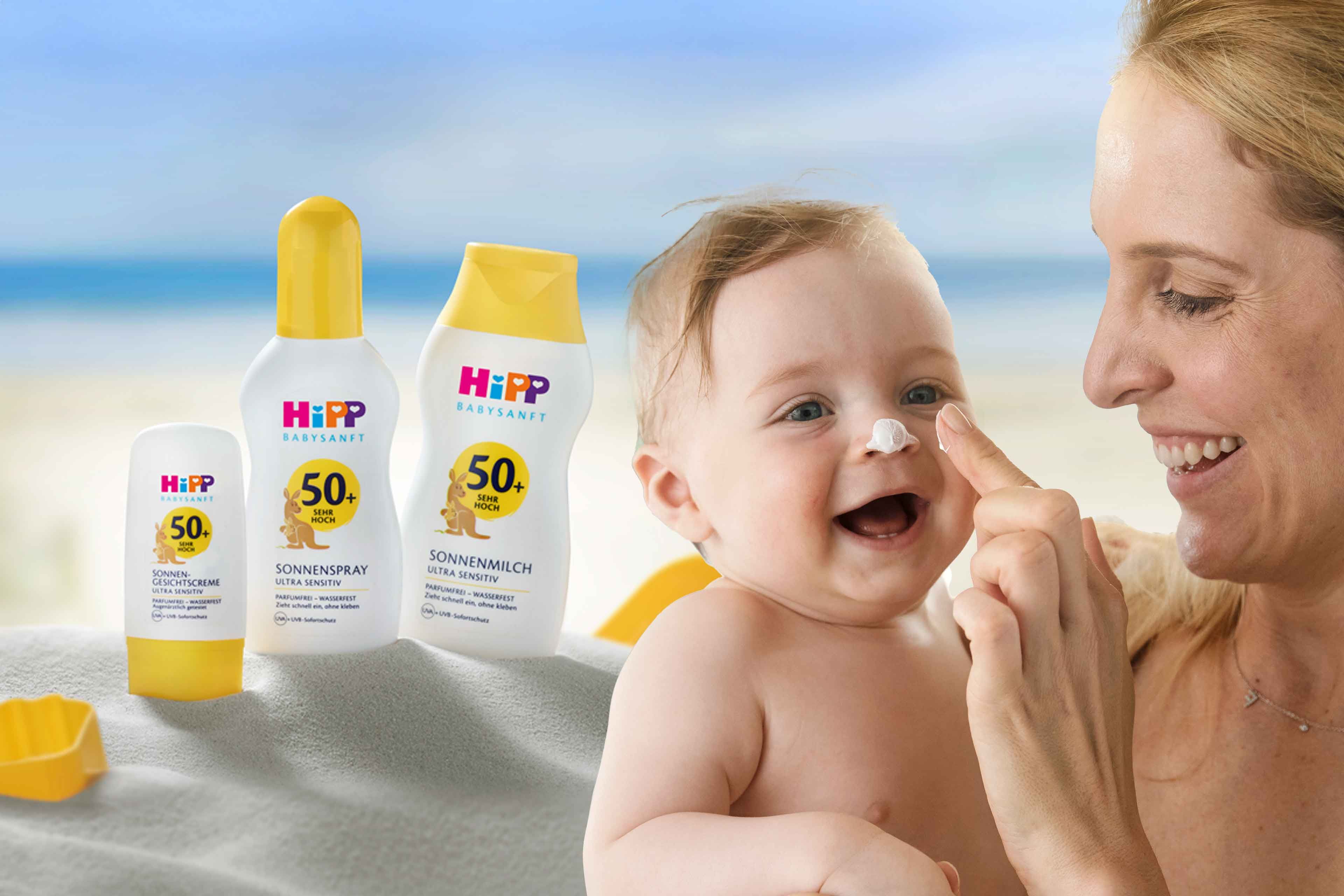 Ein Baby, das mit der Hand einer Frau Sonnenschutzmittel aufträgt, begleitet von verschiedenen Sonnenschutzmitteln mit LSF-Werten.