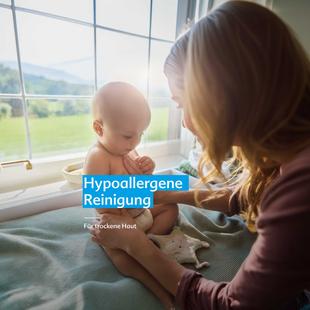 Mutter hält Baby sitzend auf einer Fensterbank mit grüner Landschaft im Hintergrund