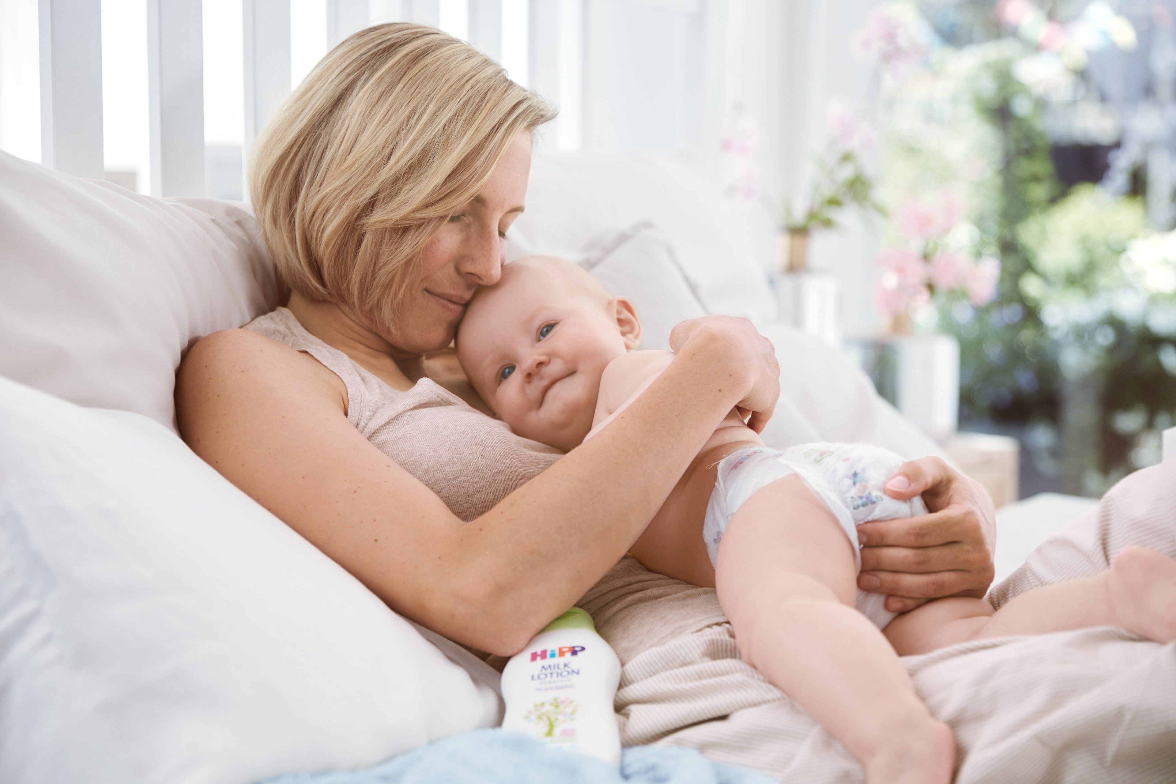 Ein zärtlicher Moment zwischen einer Frau und einem Baby, wobei die Frau das Baby sanft an ihr Gesicht drückt.