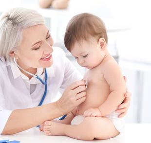 Eine medizinische Fachkraft, die ein Baby in einer klinischen Umgebung betreut.