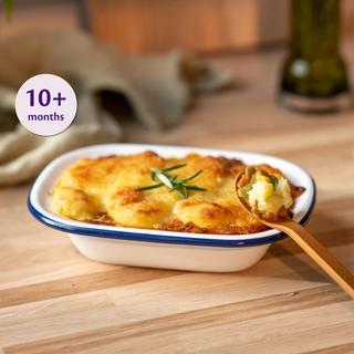 Mini chicken and lentil mash bake with peas served on a small wooden baby plate on a marble surface