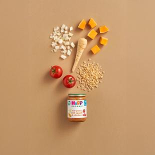 HiPP Organic Star pasta with Squash & Chicken jar surrounded by tomatoes, squash, parsnip and star-shaped pasta on a neutral background