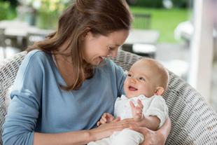 Eine Mutter hält ihr lächelndes Baby im Arm