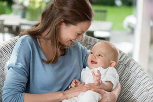 Eine Mutter hält ihr lächelndes Baby im Arm