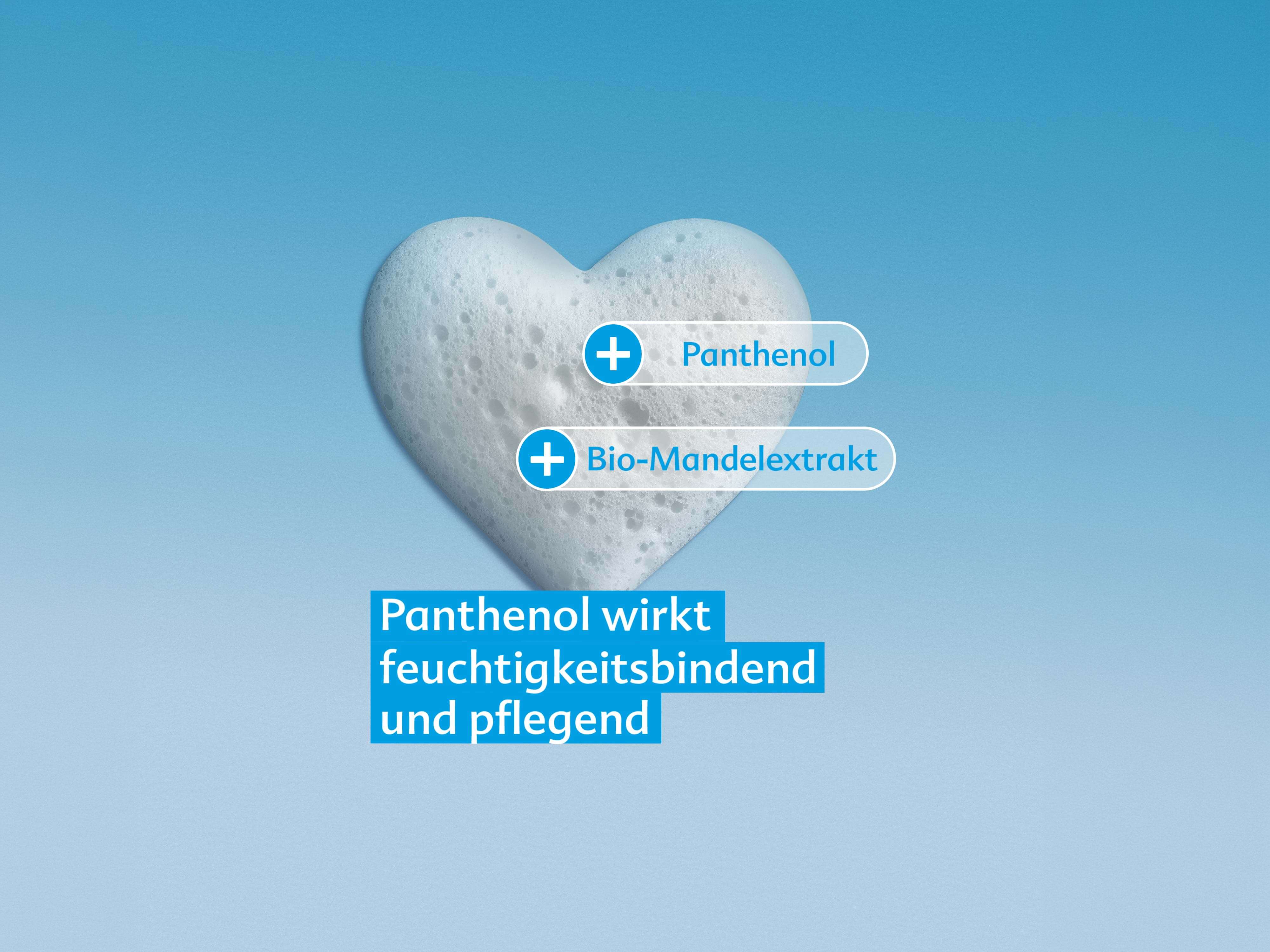 Herzförmiger Schaum vor blauem Hintergrund mit Beschriftungen 'Panthenol' und 'Bio-Mandelextrakt' sowie Text 'Panthenol wirkt feuchtigkeitsbindend und pflegend'