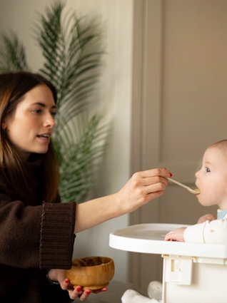 Mum feeding baby breakfast from bamboo bowl