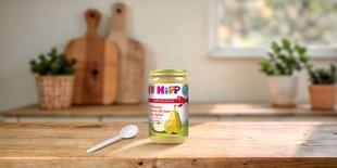 HiPP Bio Vorteils-Glas Williams-Christ-Birnen mit Apfel auf Holztisch in heller, gemütlicher Küche mit Löffel im Vordergrund