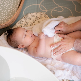 Mum putting babies nappy on after a bath