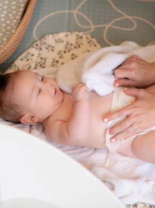 Mum putting babies nappy on after a bath