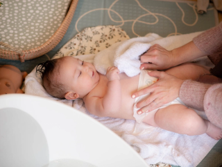 Mum putting babies nappy on after a bath