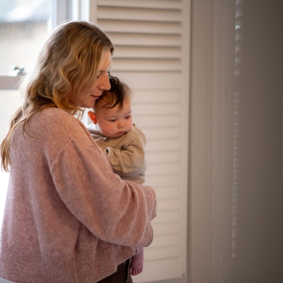 Mum holding baby on hip walking around bedroom