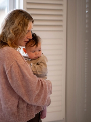 Mum holding baby on hip walking around bedroom