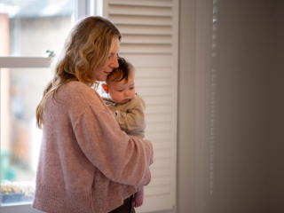 Mum holding baby on hip walking around bedroom