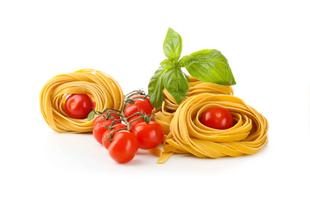 Ein lebhaftes Arrangement aus frischen Nudeln, Kirschtomaten und Basilikumblättern vor einem weißen Hintergrund.
