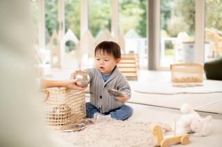 toddler playing with toys on the floor wearing a grey jumper and blue pants