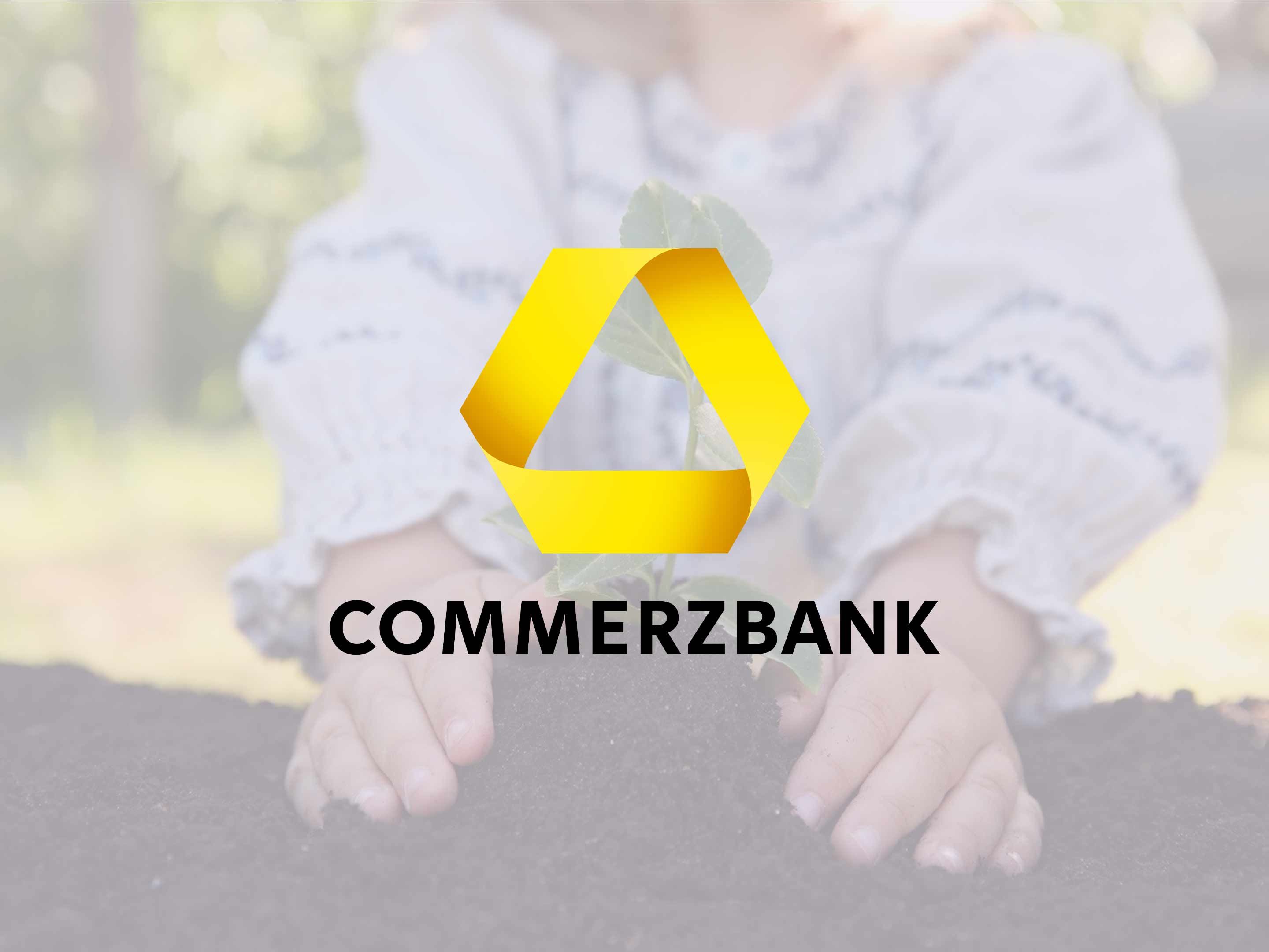 Gelbes Commerzbank-Logo über den Händen eines Kindes, das eine kleine Pflanze im Boden hält