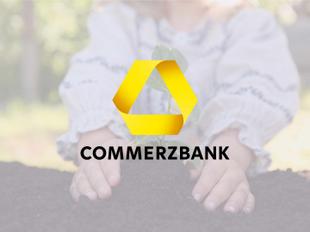 Babyhände pflanzen einen kleinen Setzling in die Erde, darüber das gelbe Commerzbank-Logo mit Schriftzug.