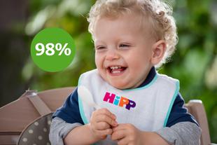 Fröhlich lachendes Baby im Hochstuhl mit HiPP-Lätzchen, daneben grüner Kreis mit „98 %“ Zufriedenheit der Eltern.