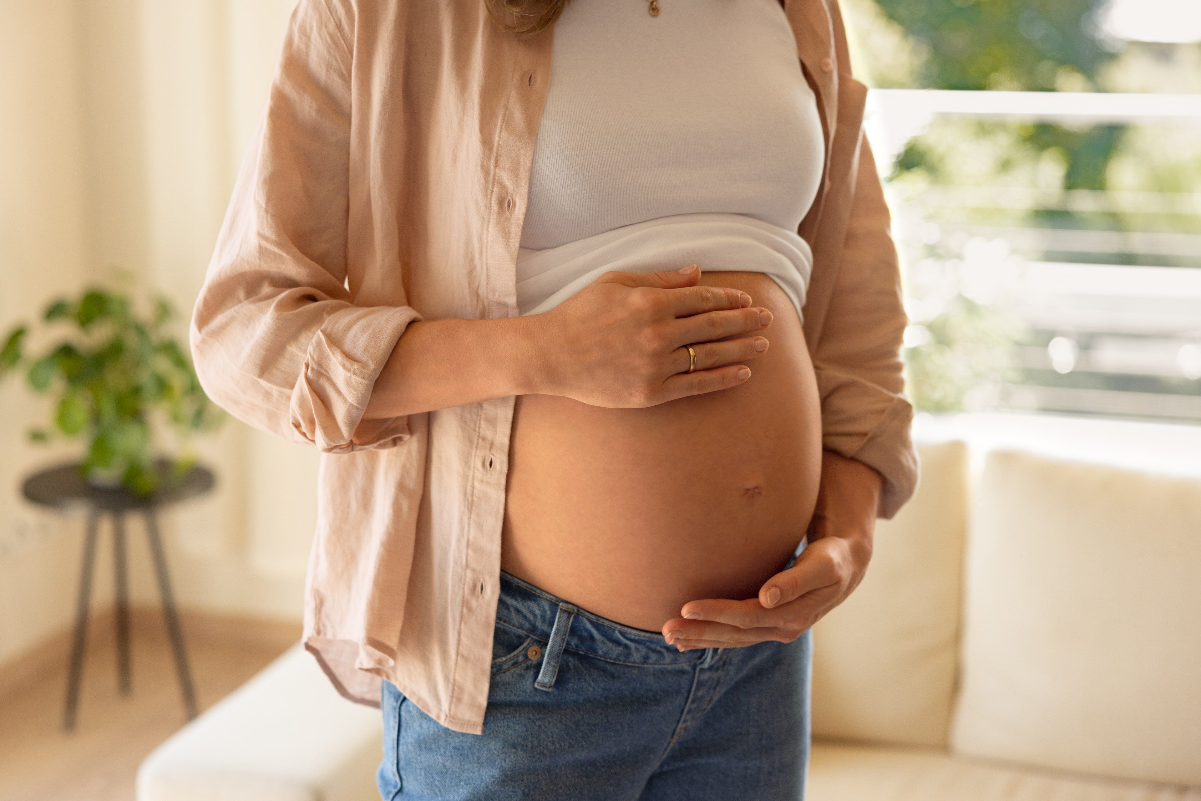 Eine Person, die vermutlich schwanger ist, berührt sanft ihren Bauch.