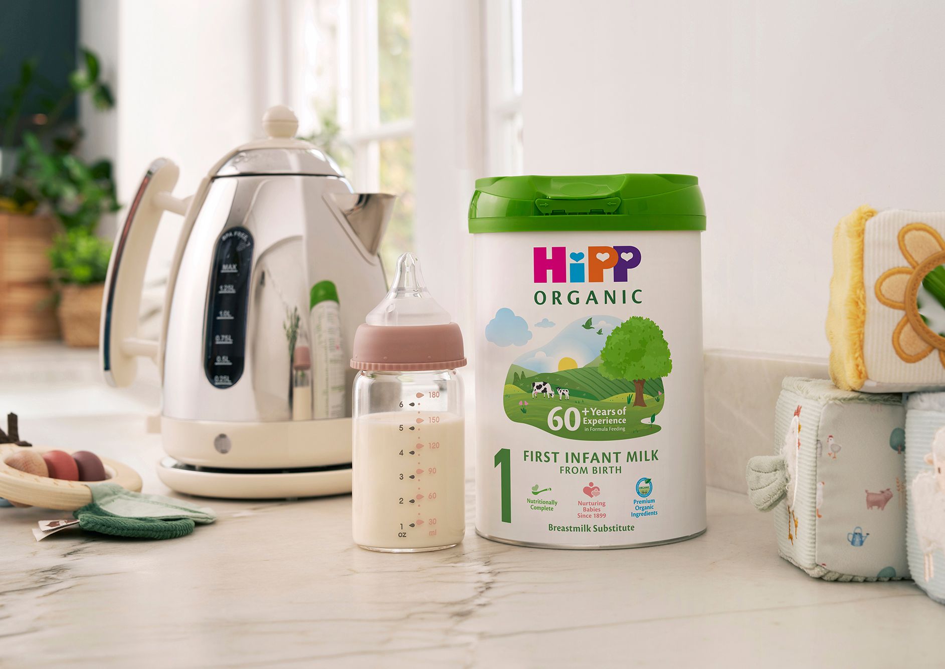 HiPP Organic First Infant Milk Powder Tin on a kitchen worktop next to a bottle of milk