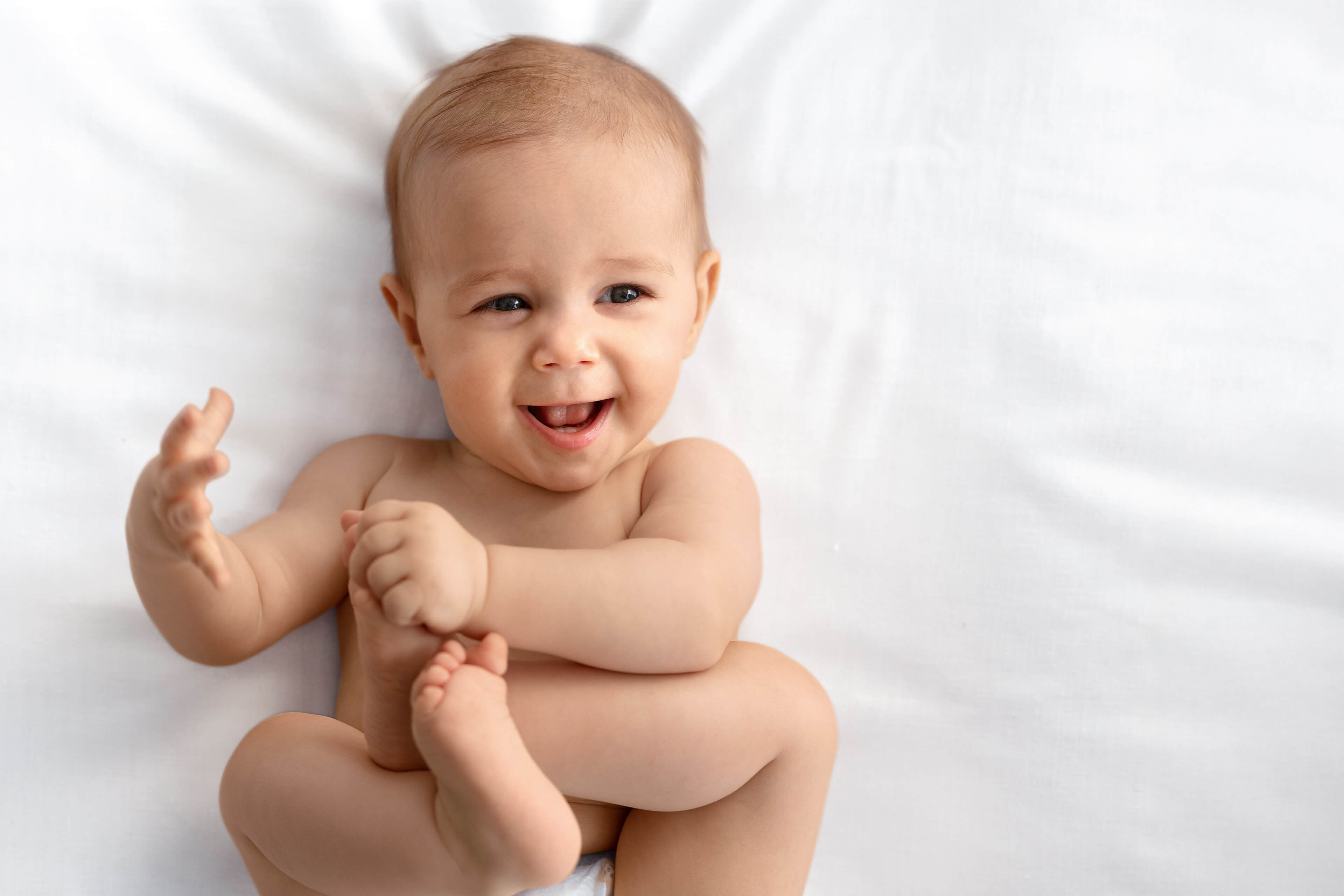 Ein Baby mit einem freudigen Gesichtsausdruck, das seine Hand ausstreckt.