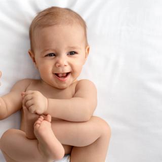 Ein Baby mit einem freudigen Gesichtsausdruck, das seine Hand ausstreckt.