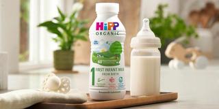 First infant milk ready to feed 470ml bottle next to a milk bottle on a kitchen worktop