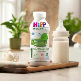 First infant milk ready to feed 470ml bottle next to a milk bottle on a kitchen worktop