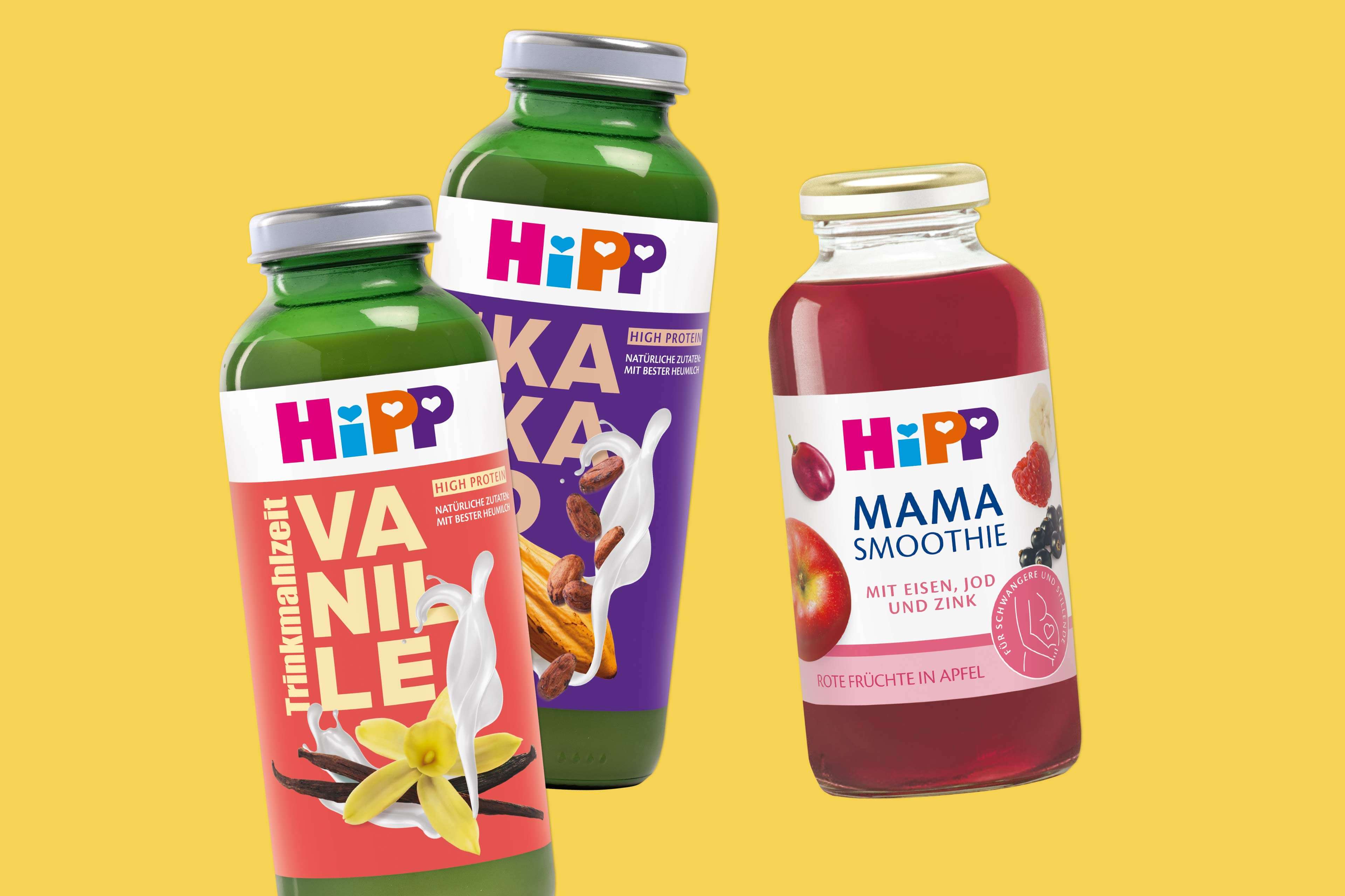 Drei HiPP-Getränkeflaschen mit den Sorten Vanille, Kakao und Mama Smoothie vor gelbem Hintergrund